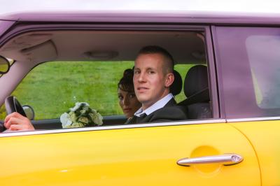 Femme souriante portant un blazer imprimé coloré, un t-shirt gris et un jean, posant devant un fond blanc.