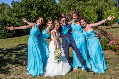 Femme souriante portant un blazer imprimé coloré, un t-shirt gris et un jean, posant devant un fond blanc.