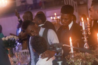 Femme souriante portant un blazer imprimé coloré, un t-shirt gris et un jean, posant devant un fond blanc.