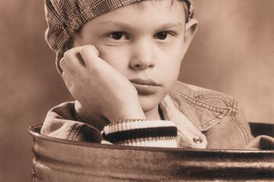 Femme souriante portant un blazer imprimé coloré, un t-shirt gris et un jean, posant devant un fond blanc.