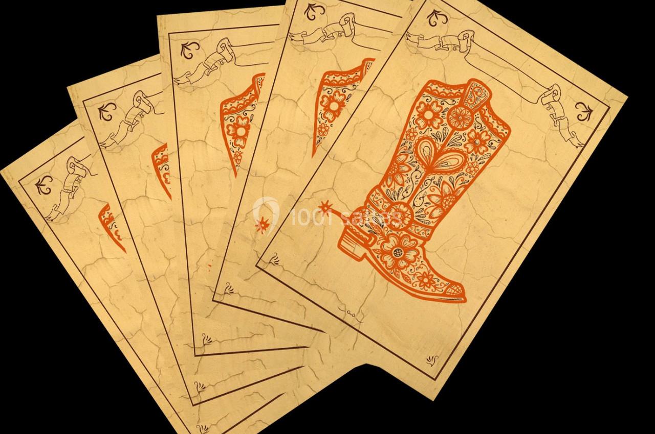 Illustration de cartes à jouer ornées d'une botte décorative orange sur un fond beige vieilli.