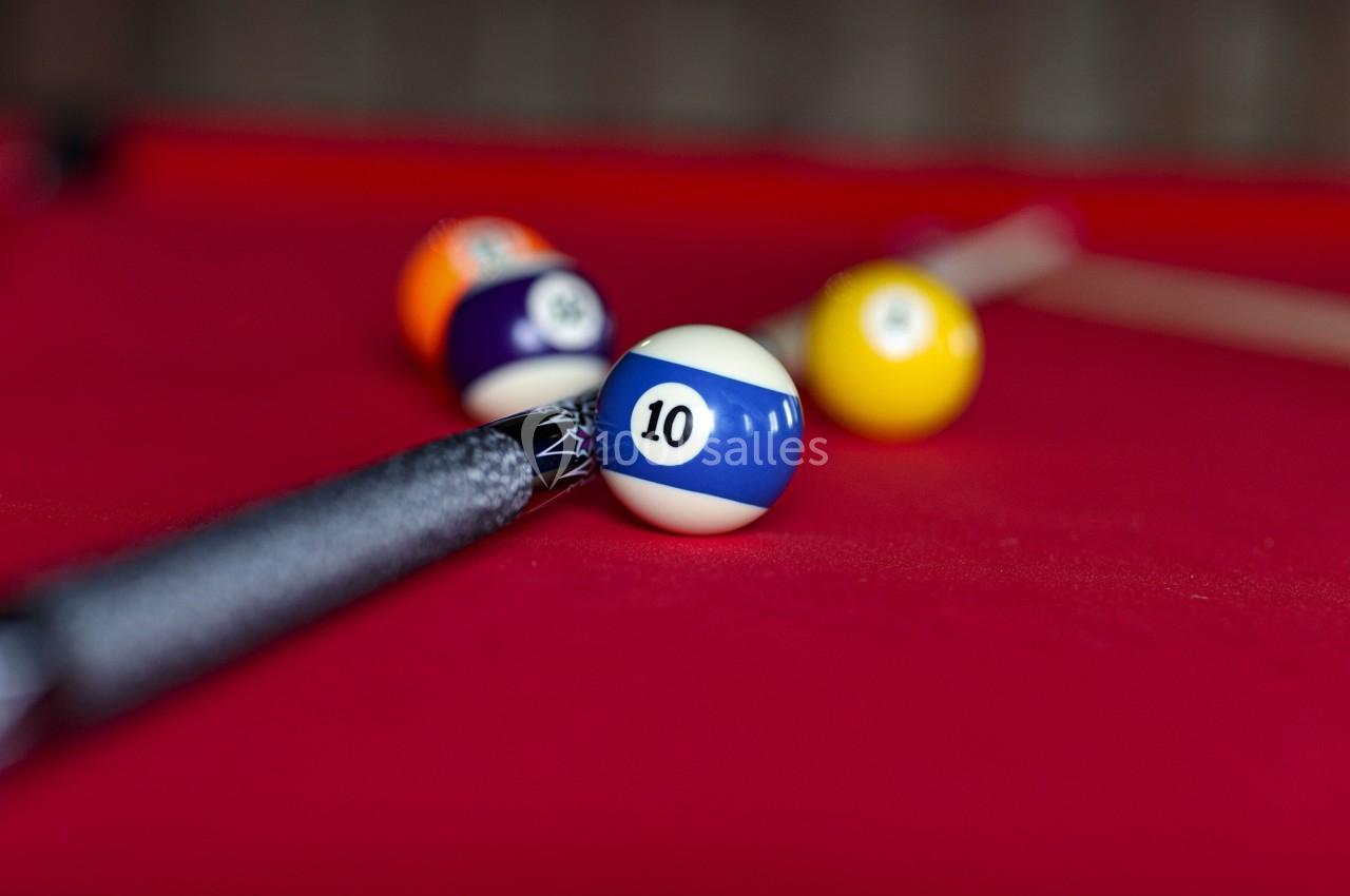 Bille de billard numéro 10 bleue et blanche sur une table rouge, avec une queue de billard en arrière-plan.