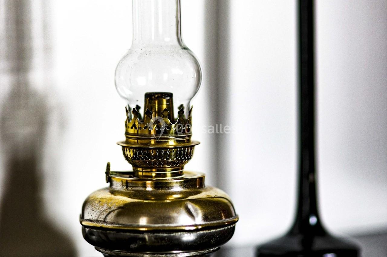 Lampe à huile ancienne en métal doré avec un verre transparent, posée sur une surface sombre.