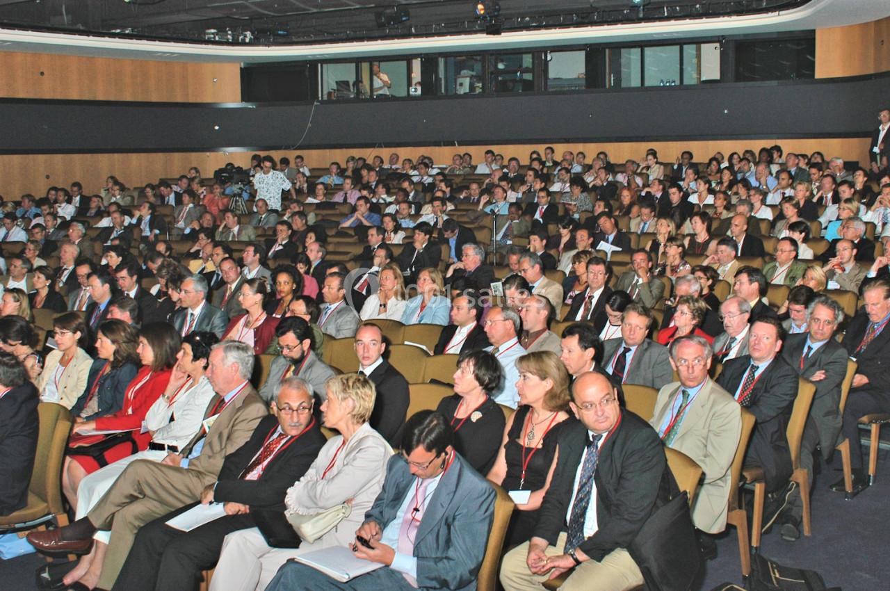 Salle comble avec un public assis, composé de participants attentifs lors d'une conférence ou d'un événement professionnel.