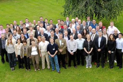 Miniature Freddy Smeets Photographies #12 Un groupe d'adultes posant en extérieur sur une pelouse verte, avec un arbre en arrière-plan.