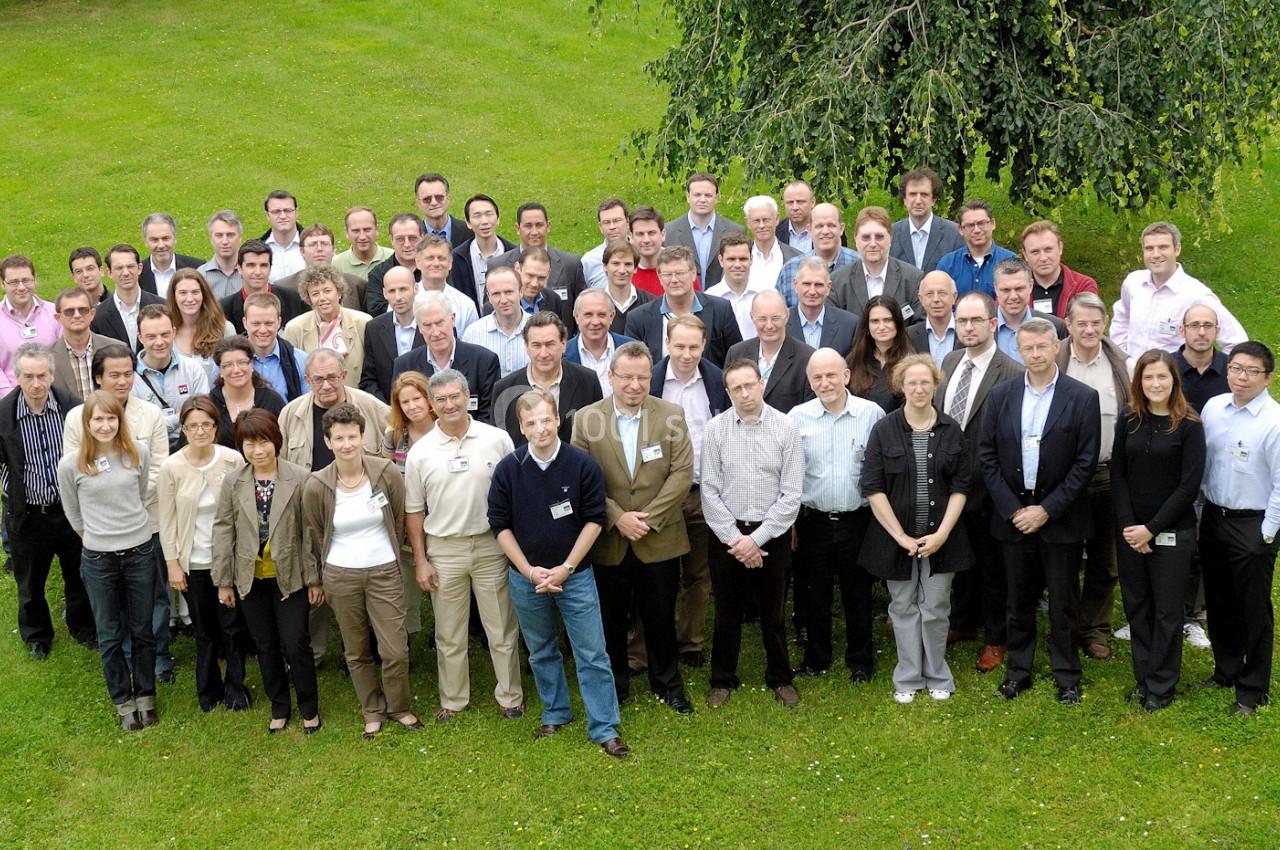 Un groupe d'adultes posant en extérieur sur une pelouse verte, avec un arbre en arrière-plan.