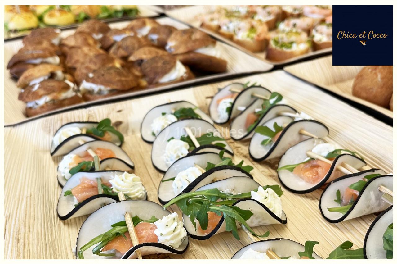 Plateaux de bouchées apéritives variées avec des roulés au saumon, fromage frais et roquette, présentés sur des assiettes en…