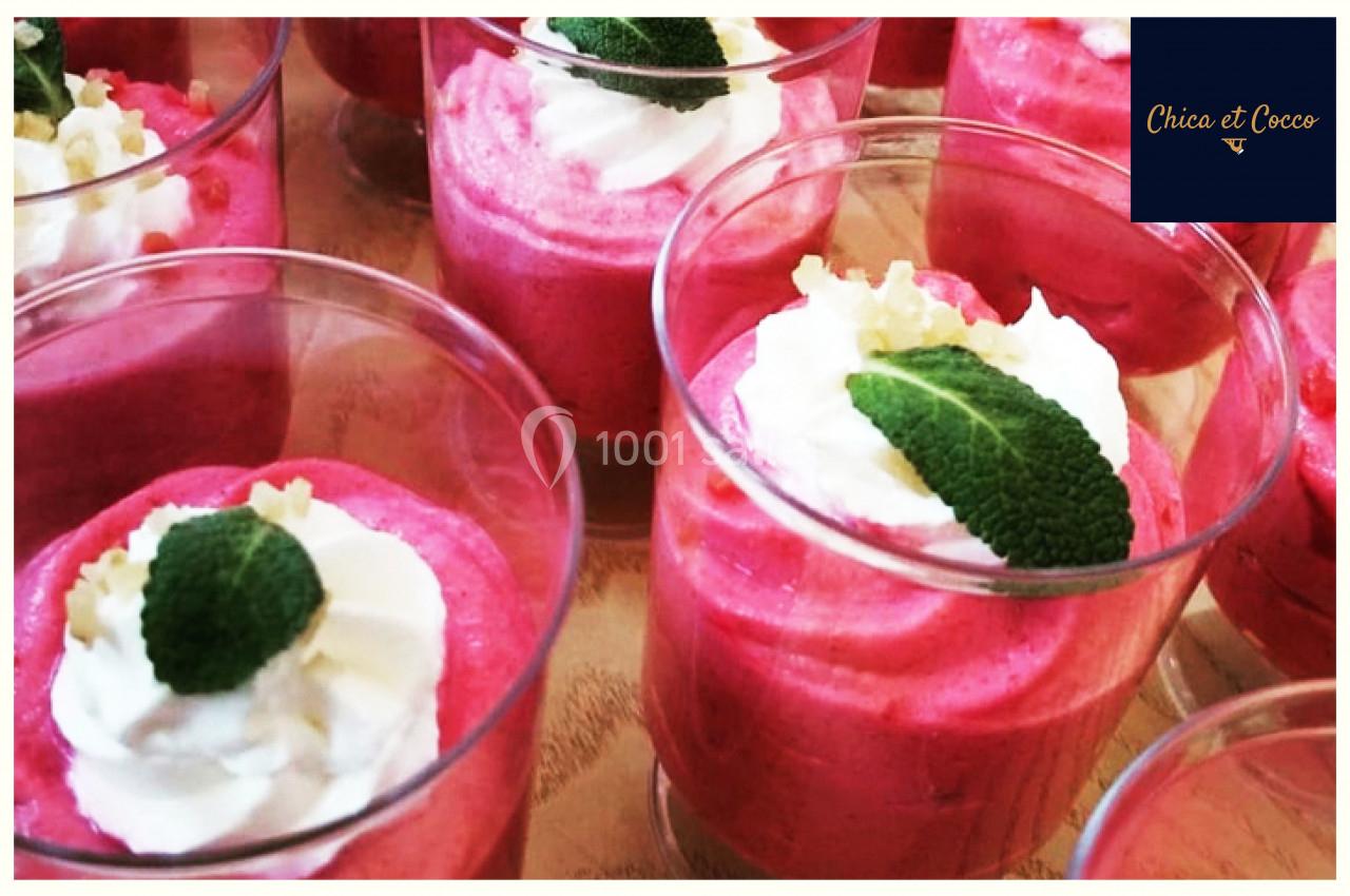 Verrines de mousse rose garnies de crème fouettée, feuilles de menthe et éclats décoratifs.
