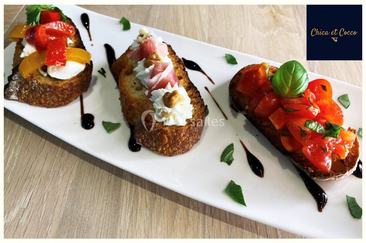 Assortiment de bruschettas garnies de légumes, fromage et jambon, présenté sur une assiette blanche avec sauce balsamique.