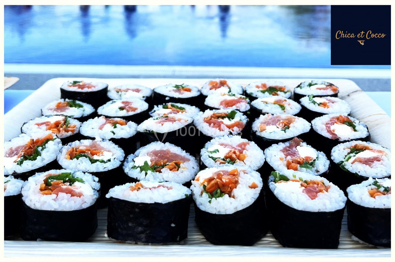 Plateau de makis variés avec garnitures de poisson, légumes et riz, présenté sur une table en extérieur.