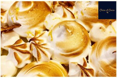 Assiette garnie de beignets dorés en forme de demi-lune, présentée sur une table avec une coupe en arrière-plan.