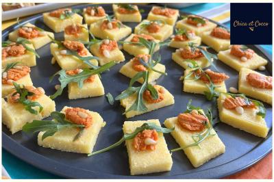 Assiette garnie de beignets dorés en forme de demi-lune, présentée sur une table avec une coupe en arrière-plan.