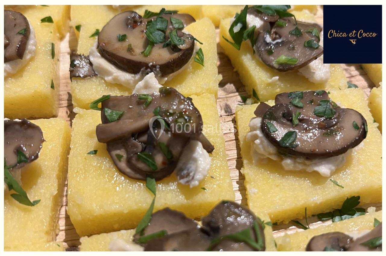 Carrés de polenta garnis de champignons sautés, fromage frais et persil haché, disposés sur une planche en bois.
