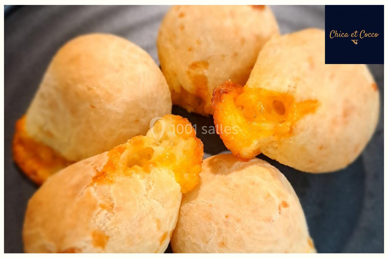 Quatre petits pains dorés au fromage, légèrement ouverts, présentés sur une assiette sombre.