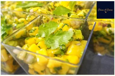 Assiette garnie de beignets dorés en forme de demi-lune, présentée sur une table avec une coupe en arrière-plan.