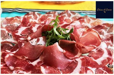 Assiette garnie de beignets dorés en forme de demi-lune, présentée sur une table avec une coupe en arrière-plan.