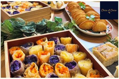 Assiette garnie de beignets dorés en forme de demi-lune, présentée sur une table avec une coupe en arrière-plan.