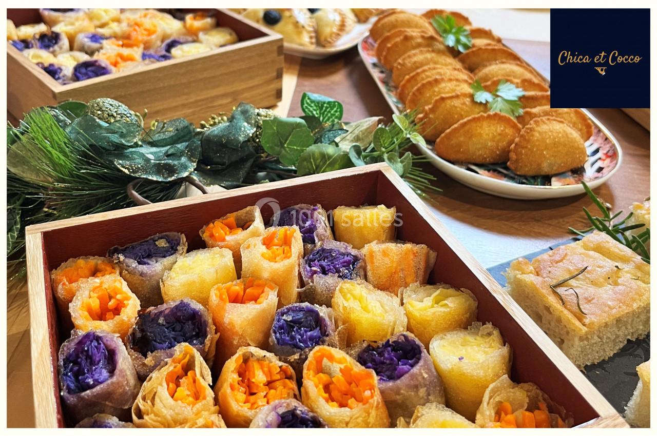 Plateaux de rouleaux de légumes colorés, feuilletés dorés et focaccia, présentés sur une table décorée.