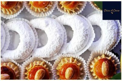 Assiette garnie de beignets dorés en forme de demi-lune, présentée sur une table avec une coupe en arrière-plan.