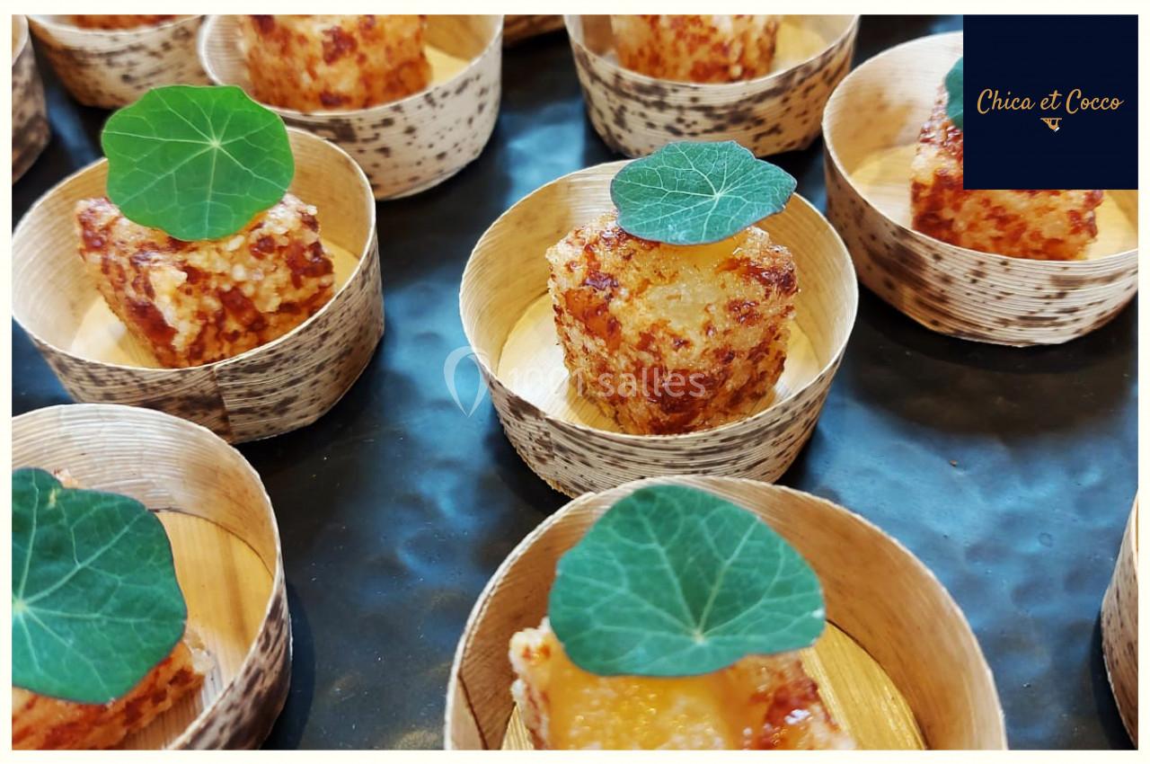 Bouchées dorées servies dans des coupelles en bois, garnies de feuilles vertes décoratives.