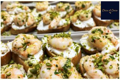 Assiette garnie de beignets dorés en forme de demi-lune, présentée sur une table avec une coupe en arrière-plan.