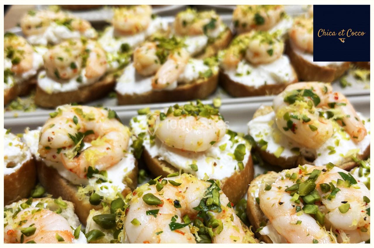 Tranches de pain garnies de fromage frais, crevettes et éclats de pistaches, présentées sur un plateau.