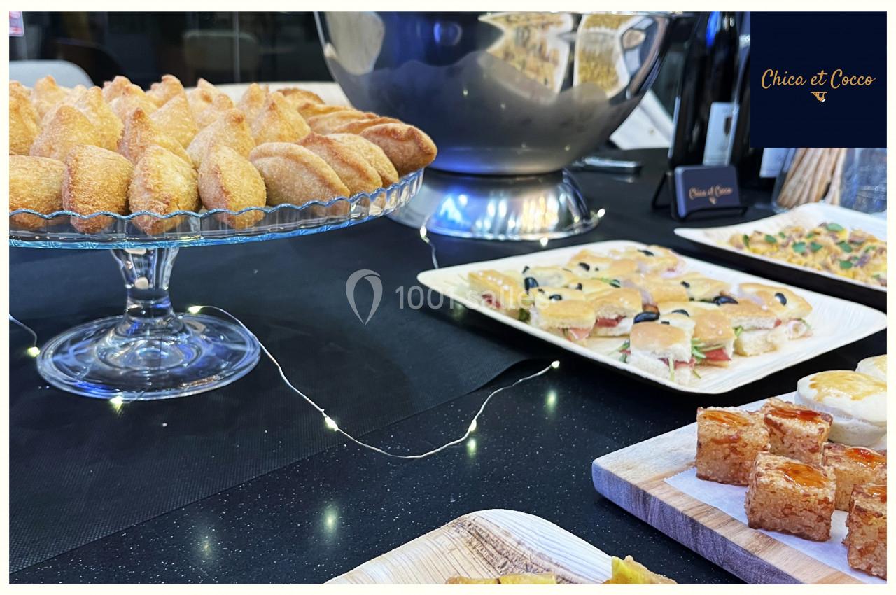 Plateau de pâtisseries salées et sucrées disposées sur une table noire avec des guirlandes lumineuses.
