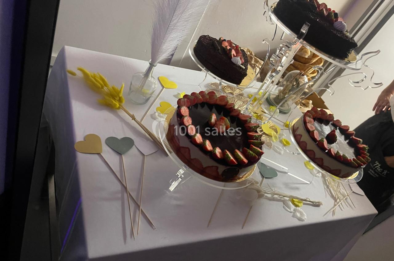 Gâteaux au chocolat décorés de fraises sur une table blanche, entourés de décorations en forme de cœurs colorés.