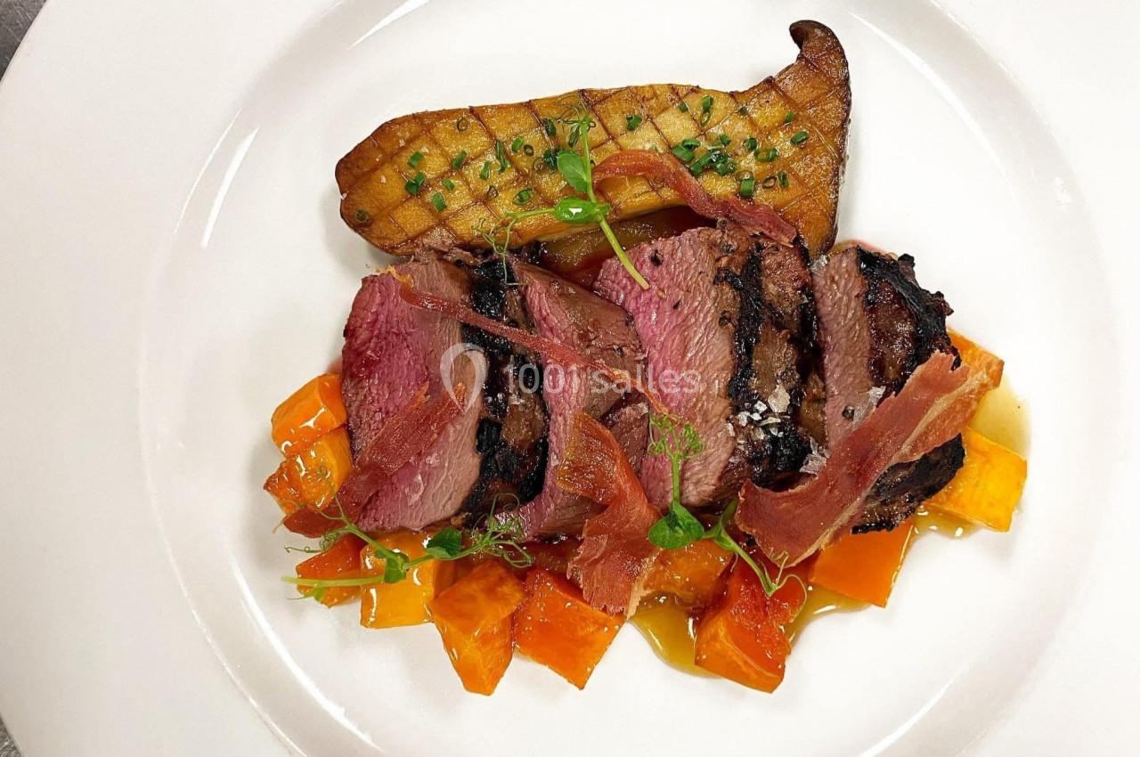 Assiette gastronomique avec magret de canard tranché, patate douce, chips de jambon et garniture de poireau grillé.