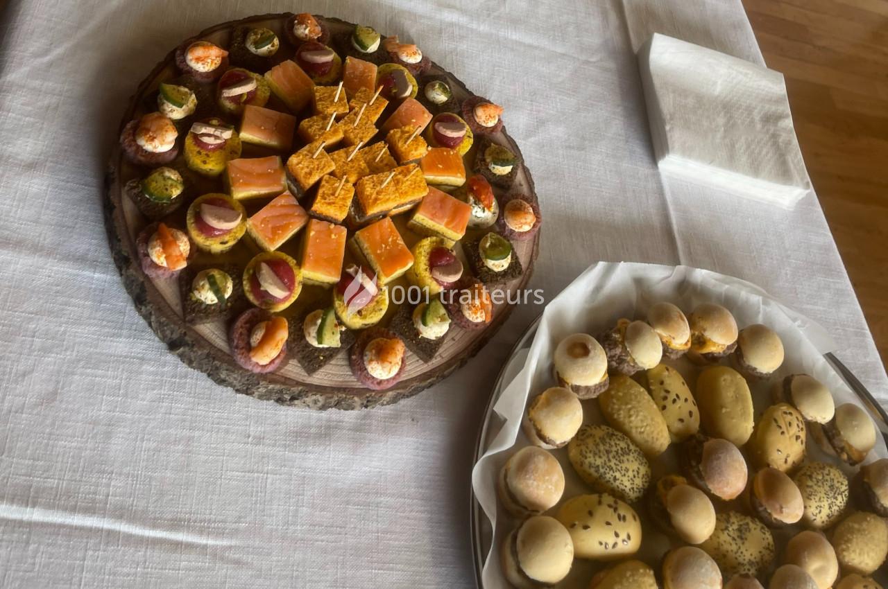 Plateaux de mignardises salées et pains variés disposés sur une table recouverte d'une nappe blanche.