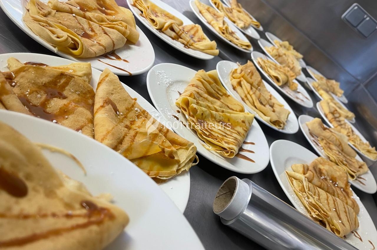 Assiettes de crêpes pliées, garnies de caramel, disposées sur un plan de travail en cuisine.