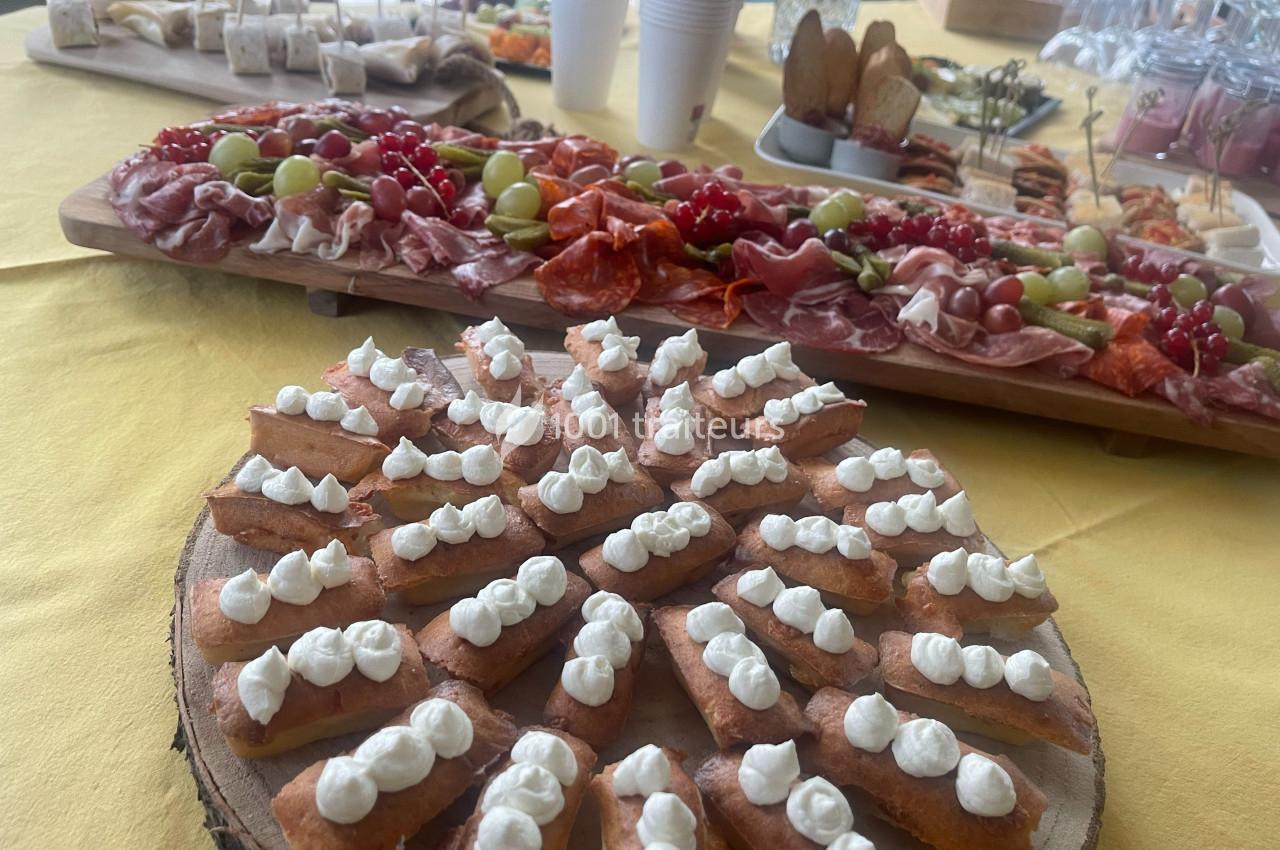 Plateau de toasts garnis de crème, accompagné de charcuteries, fruits et autres amuse-bouches sur une table jaune.