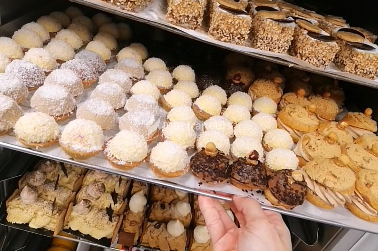 Plateaux de pâtisseries variées, incluant des choux garnis et des desserts enrobés de chocolat et de noix.