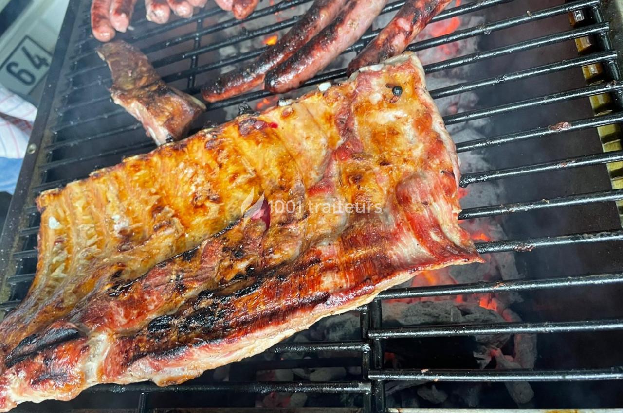 Côtes de porc et saucisses grillant sur un barbecue au charbon de bois.