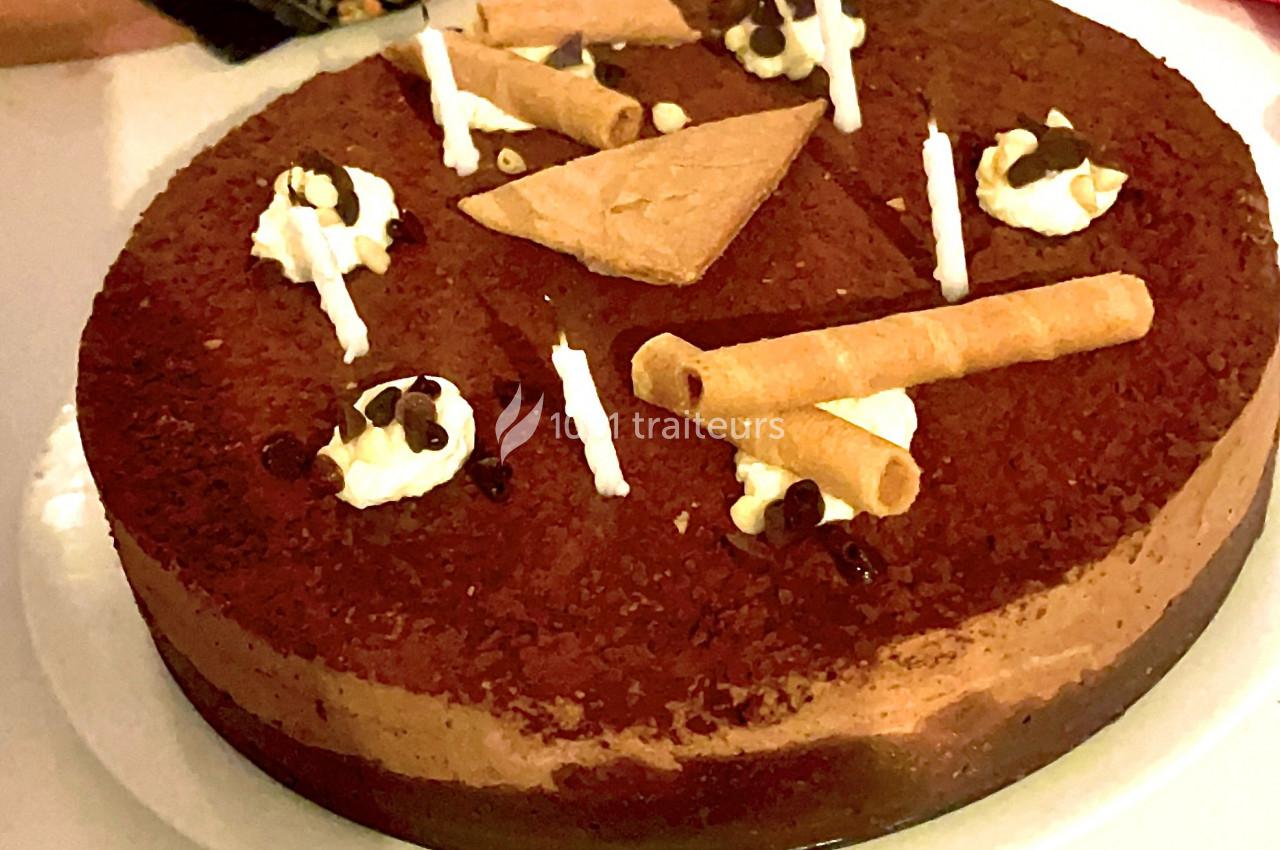 Gâteau au chocolat décoré de biscuits, de crème chantilly et de pépites de chocolat, présenté sur une assiette blanche.