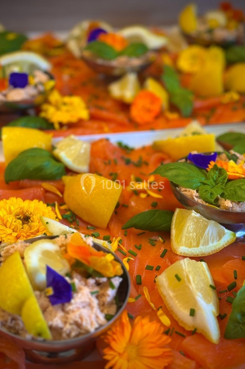 Plateau de saumon fumé garni de rondelles de citron, fleurs comestibles et herbes fraîches.