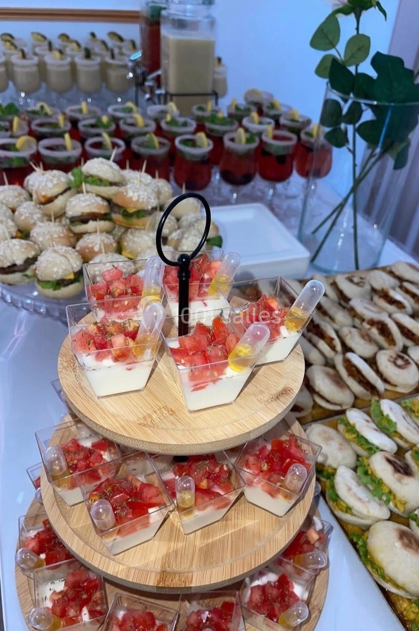 Buffet avec verrines de dessert, mini-sandwiches, roulés salés et desserts en arrière-plan.