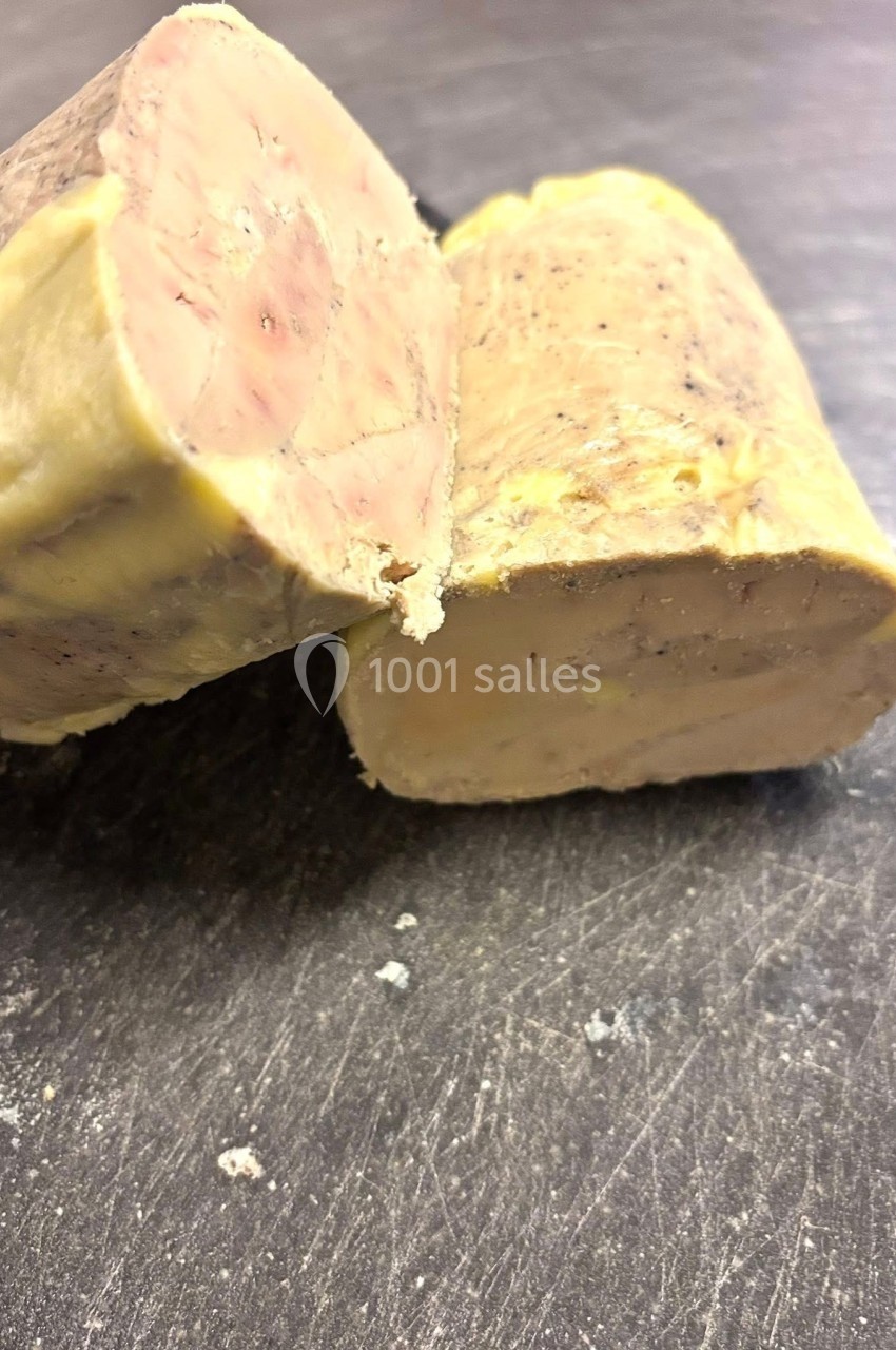 Deux morceaux de foie gras coupés en biais, posés sur une surface sombre.
