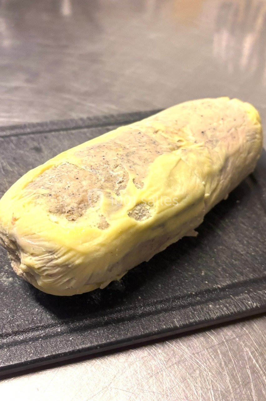 Bloc de préparation alimentaire enrobé d'une couche jaune, posé sur une planche noire sur une surface métallique.