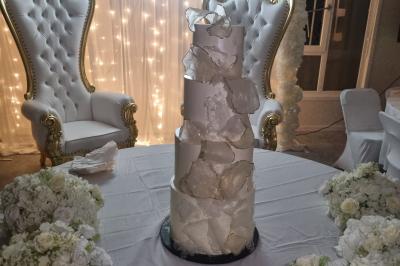 Table décorée avec des flûtes en verre, un bouquet de fleurs blanches, une bougie et des fauteuils ornés en arrière-plan.