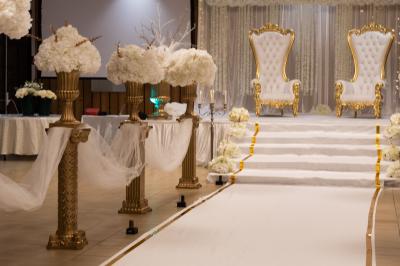 Table décorée avec des flûtes en verre, un bouquet de fleurs blanches, une bougie et des fauteuils ornés en arrière-plan.
