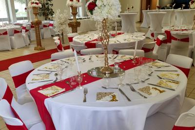 Table décorée avec des flûtes en verre, un bouquet de fleurs blanches, une bougie et des fauteuils ornés en arrière-plan.