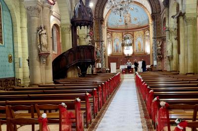 Table décorée avec des flûtes en verre, un bouquet de fleurs blanches, une bougie et des fauteuils ornés en arrière-plan.