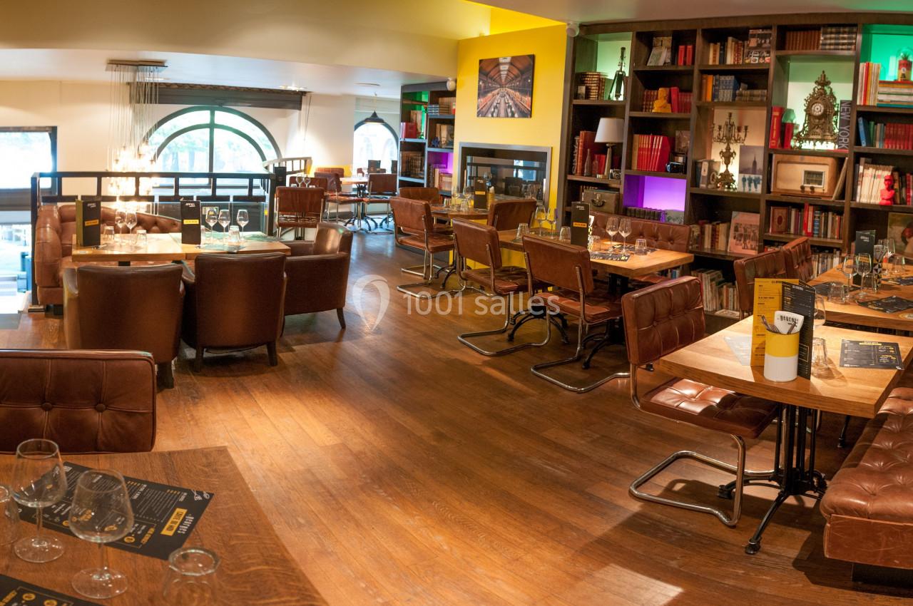 Salle de restaurant chaleureuse avec mobilier en cuir, étagères décorées et lumière tamisée.