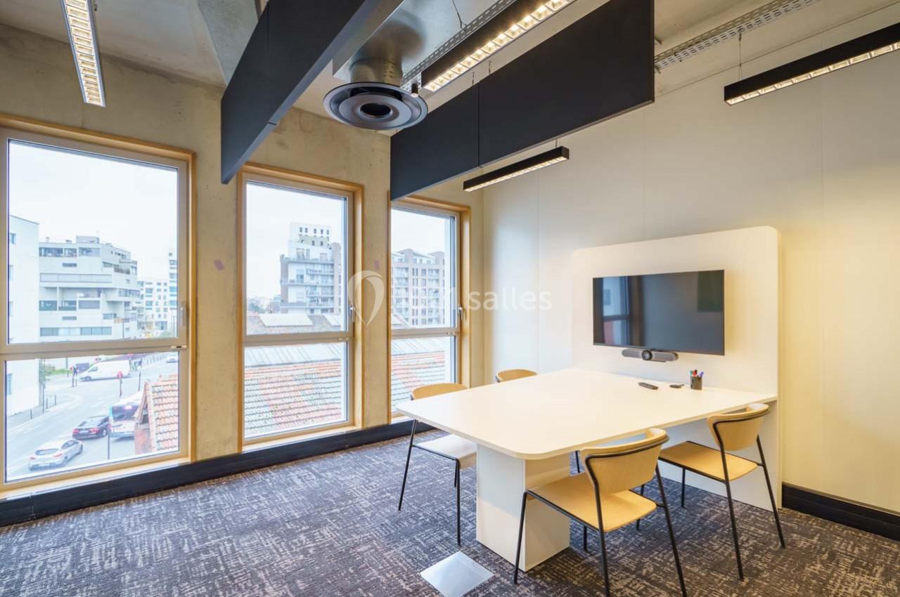 Location salle Ivry-sur-Seine (Val-de-Marne) - Walter Ivry #11 Salle de réunion lumineuse avec une table blanche, quatre chaises, un écran mural et de grandes fenêtres donnant sur des…