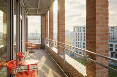Miniature Location salle Ivry-sur-Seine (Val-de-Marne) - Walter Ivry #6 Bâtiment moderne en briques avec de grandes fenêtres, entouré de végétation et de parasols jaunes au premier plan.