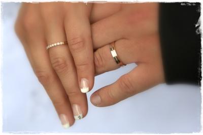 Femme en robe de mariée blanche tenant un bouquet de fleurs blanches et décorations bleues, en extérieur sur pelouse.