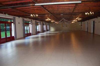 Cuisine professionnelle avec carrelage beige, plans de travail en inox, évier, réfrigérateur et éclairage fluorescent.