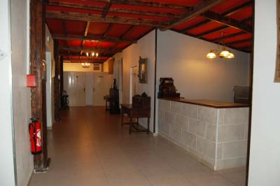 Cuisine professionnelle avec carrelage beige, plans de travail en inox, évier, réfrigérateur et éclairage fluorescent.