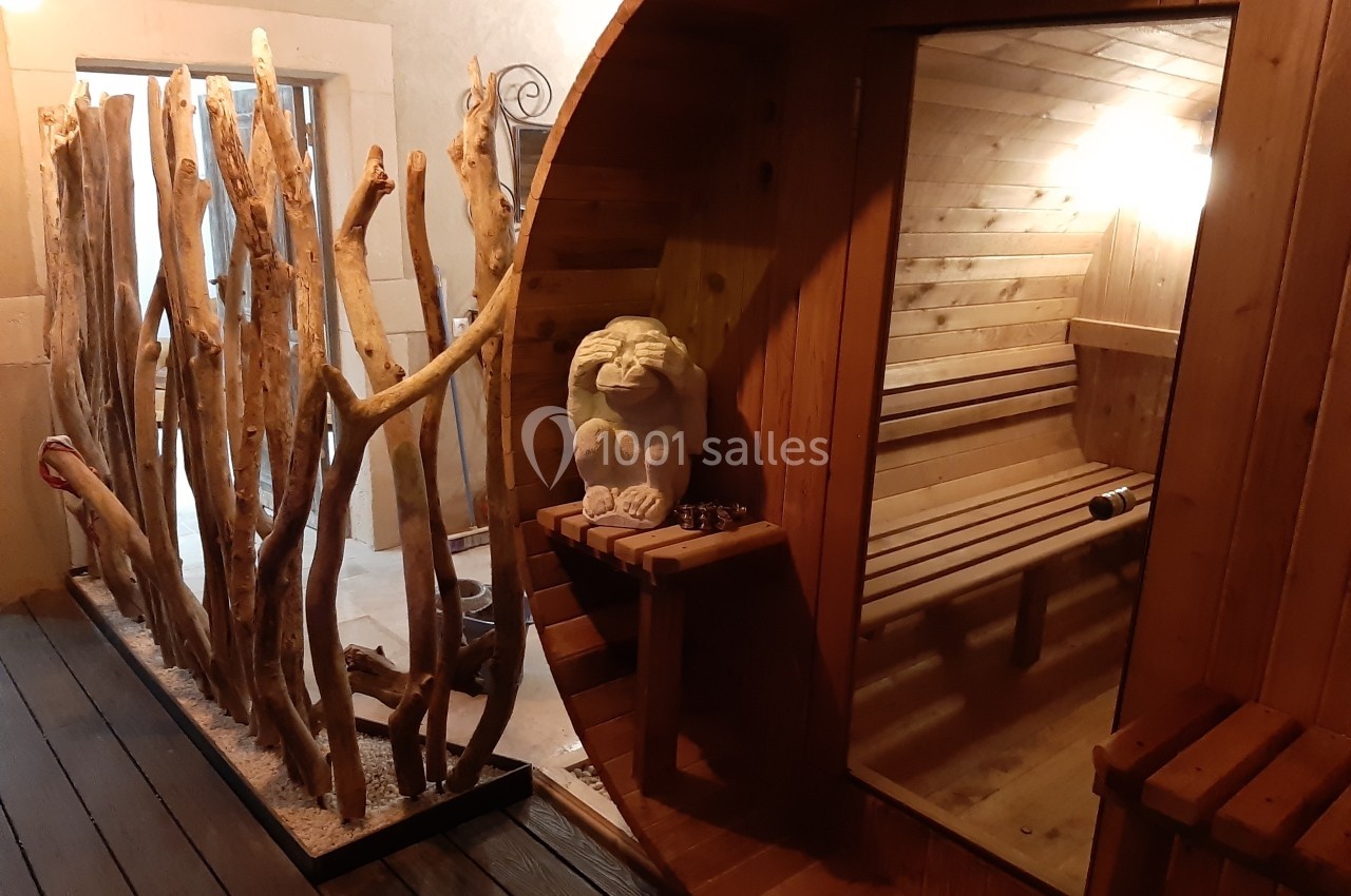 Cabine de sauna en bois avec bancs, miroir et décoration en branches naturelles dans un espace détente.